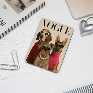 Peut inclure: Une couverture de magazine Vogue beige avec trois chiens portant des lunettes de soleil et des tenues à la mode. Les chiens sont un teckel, un terrier et un berger allemand. La couverture du magazine est sur une surface blanche.