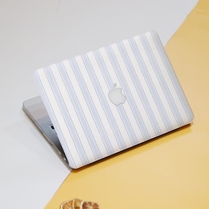 May include: A white laptop computer with a blue and white striped design. The laptop has an Apple logo on the lid.