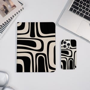 May include: A notebook and phone case with a black and cream-colored abstract pattern. The notebook is rectangular and the phone case is a rectangle with rounded corners. The pattern consists of curved, elongated shapes.