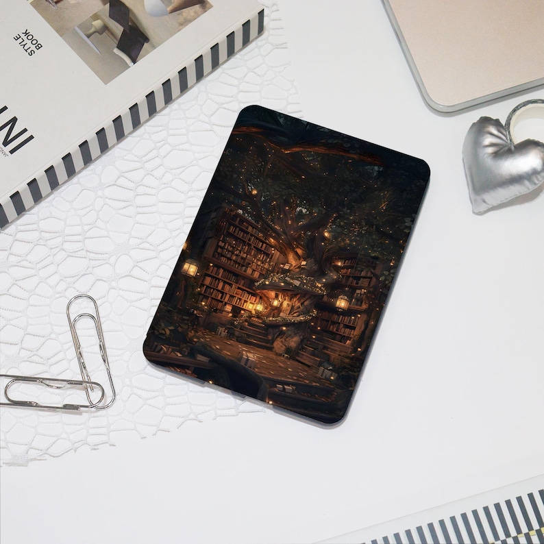 K&ouml;nnte beinhalten: Eine schwarze Tablet-H&uuml;lle mit einer detaillierten Illustration einer Fantasy-Bibliothek in einem Baum, beleuchtet von warmen Lichtern. Das Design erzeugt eine gem&uuml;tliche, magische Atmosph&auml;re, ideal f&uuml;r B&uuml;cherliebhaber.