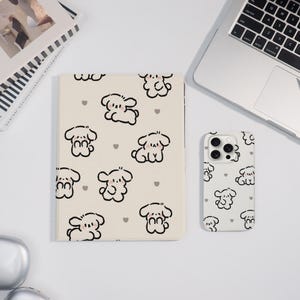 May include: A cream-colored tablet case and a white phone case, both featuring a repeating pattern of cartoon dog illustrations and small gray hearts. The tablet case is rectangular, and the phone case has a camera cutout.
