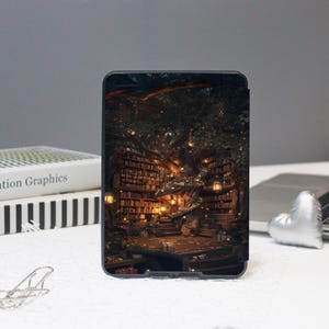 K&ouml;nnte beinhalten: Eine schwarze Tablet-H&uuml;lle mit einer detaillierten Illustration einer Fantasy-Bibliothek in einem Baum. Das Kunstwerk zeigt B&uuml;cherregale, warme Beleuchtung und einen gem&uuml;tlichen Lesebereich, der eine skurrile Szene schafft.