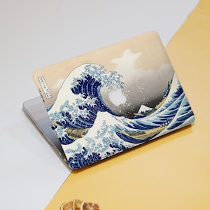 May include: A laptop skin featuring a blue and white image of a large wave crashing against a mountain. The wave is depicted in a Japanese style, with a traditional Japanese design. The skin is made from a durable material and is designed to protect your laptop from scratches and wear.