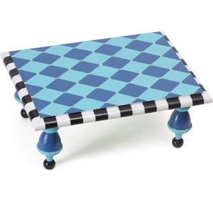 May include: A square decorative table with a blue and turquoise diamond pattern top. The table's edges are black and white striped. The legs are blue with black ball feet. A whimsical accent piece.