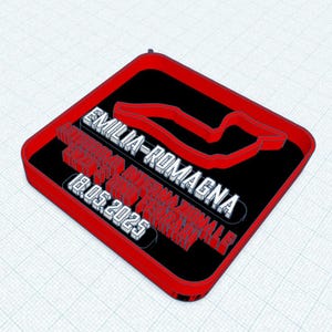 Op de afbeelding: Een vierkant bord in zwart en rood met de tekst "Emilia-Romagna" en "Autodromo Internazionale Enzo e Dino Ferrari" en de datum "18.05.2025". Het bord heeft ook een rode omtrek van een racecircuit.