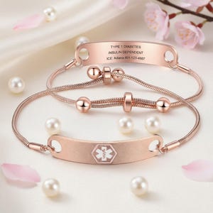 Può includere: Due braccialetti di allerta medica in oro rosa con dettagli di perle. Un braccialetto ha il testo "TYPE 1 DIABETES, INSULIN DEPENDENT, ICE: Adiana 801-123-4567". L'altro braccialetto ha un simbolo medico.