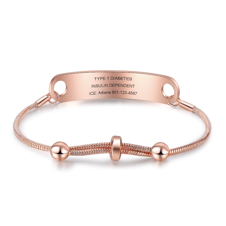 May include: Rose gold medical ID bracelet with the text "TYPE 1 DIABETES INSULIN DEPENDENT" and emergency contact information. The bracelet features a snake chain design with decorative beads.