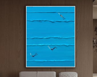 Op de afbeelding: Een rechthoekig wandkunstwerk met een levendige blauwe textuurachtergrond met horizontale verhoogde verfstreken. Drie kleine figuren van duikers zijn op verschillende dieptes in het blauwe veld geplaatst, elk met kleine witte luchtbellen.