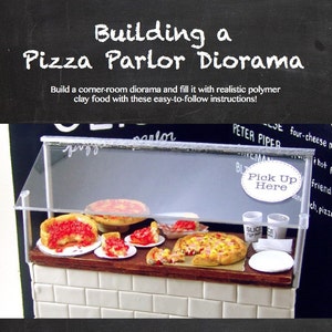 May include: A miniature pizza parlor diorama with a glass display case filled with miniature pizzas. The diorama is made of polymer clay and has a white tiled base. The sign above the display case reads "Pick Up Here". The text "Project Playbook, vol. 2 www.themousemarket.com" and "full-color photos" are written on a black chalkboard.