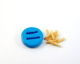 May include: A blue silicone mold for making french fries. The mold has two rows of indentations for creating the fries. There are also some finished french fries next to the mold.
