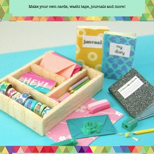 Puede incluir: Un conjunto de papelería en miniatura para casa de muñecas con un organizador de madera lleno de cinta washi de colores, tarjetas y lápices. También hay dos pequeños diarios, uno con la palabra "diario" y el otro con las palabras "mi diario".