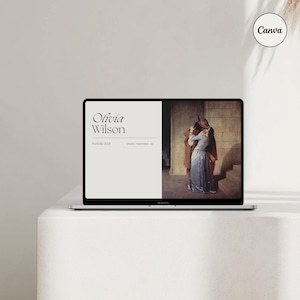 May include: A laptop computer screen displaying a website with the text "Olivia Wilson" and "Portfolio 2023" in black font on a white background. The website also features a painting of a couple embracing in a vintage style.