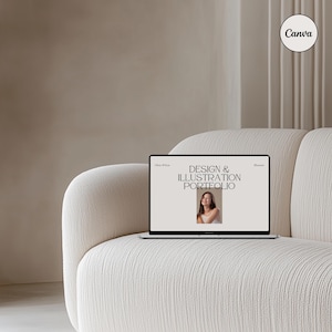 May include: A laptop computer with a white background displaying a website titled "Design & Illustration Portfolio". The website features a photo of a woman with long brown hair. The laptop is sitting on a white couch.