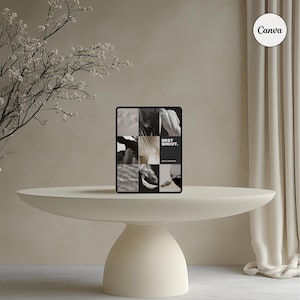 May include: A digital tablet displaying a collage of black and white images, with the text "BEST SHOOT." The tablet rests on a cream-colored, pedestal-style table. The background includes a beige wall, a white curtain, and a flowering branch.