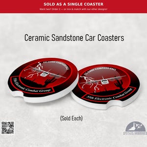 May include: Two round ceramic sandstone car coasters featuring a graphic of an EC-130H Compass Call aircraft, lightning bolts, and a desert silhouette. The text reads 55th Electronic Combat Group and EC-130H Compass Call in white lettering.