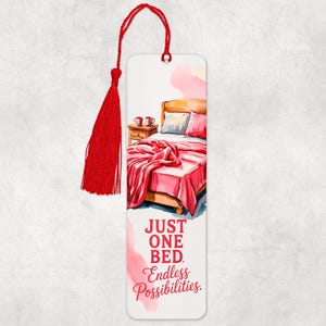 May include: A white bookmark with a watercolor illustration of a bed with a red blanket and pillows. The bookmark has a red tassel and the text "JUST ONE BED. Endless Possibilities."