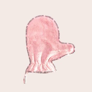 May include: A pink, mitt-shaped facial cleansing cloth. The cloth is made of a soft, plush material. The brand name "HAVREILUXE" is printed in a repeating pattern around the edge of the mitt.