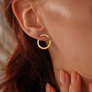 May include: Gold hoop earrings with a simple, minimalist design. The earrings are small and delicate, and they are perfect for everyday wear.