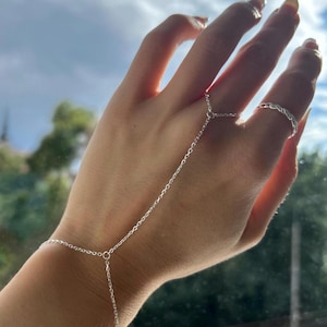 May include: A white ceramic mug with a black handle and the text "But First, Coffee" in a bold, black font. The mug is set against a blurred background, suggesting a cosy setting.