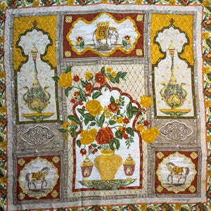 May include: A square silk scarf with an ornate design. The scarf features a central floral arrangement in a yellow vase, surrounded by framed images of elephants, horses, and decorative urns. The color palette includes yellow, red, brown, and cream.