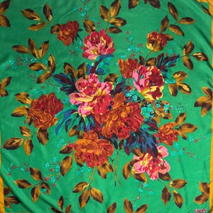 May include: Square scarf with a vibrant floral design. The scarf features a bouquet of red, pink, and orange flowers with green and blue leaves on a green background. The border is a gold color.