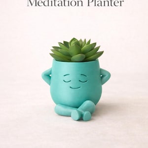 May include: A teal-colored meditation planter with a succulent plant. The planter has a smiling face and arms crossed, with legs crossed in a seated position. Text on the image reads "Calm Desk Decor Meditation Planter."