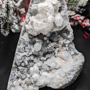 May include: A large, gray rock with a cluster of white, clear crystals. The crystals are arranged in a random pattern and some are larger than others.