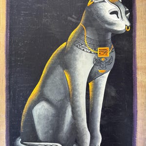 May include: A gray and gold painting of a seated cat with Egyptian-inspired jewelry and markings. The cat has a gold nose ring and is set against a black background with a purple border. The artwork has a textured appearance.