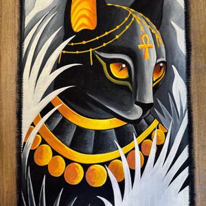 May include: A black cat painting with gold and orange accents. The cat is adorned with a gold headdress and collar, and the ankh symbol is on its forehead. The background features white and gray stylized foliage.