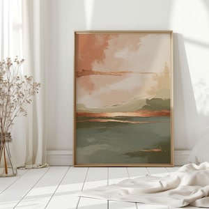 Könnte beinhalten: Abstraktes Landschaftsbild in einem goldenen Rahmen mit gedeckten Tönen von Pfirsich, Grün und Braun. Das Bild hängt an einer weißen Wand in einem Raum mit weißem Boden und einer Vase mit getrockneten Blumen.