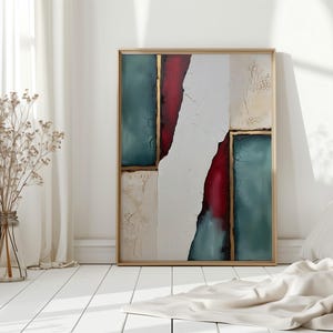 Può includere: Opera d'arte astratta incorniciata con vernice strutturata verde acqua, rossa e bianca. L'opera d'arte è in una cornice dorata e si appoggia a un muro bianco. Un vaso di vetro trasparente con fiori secchi è sul pavimento bianco.