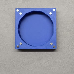 Könnte beinhalten: Ein blauer, quadratischer Rahmen aus 3D-Druck mit einem runden Ausschnitt und acht silbernen Magneten an den Kanten.