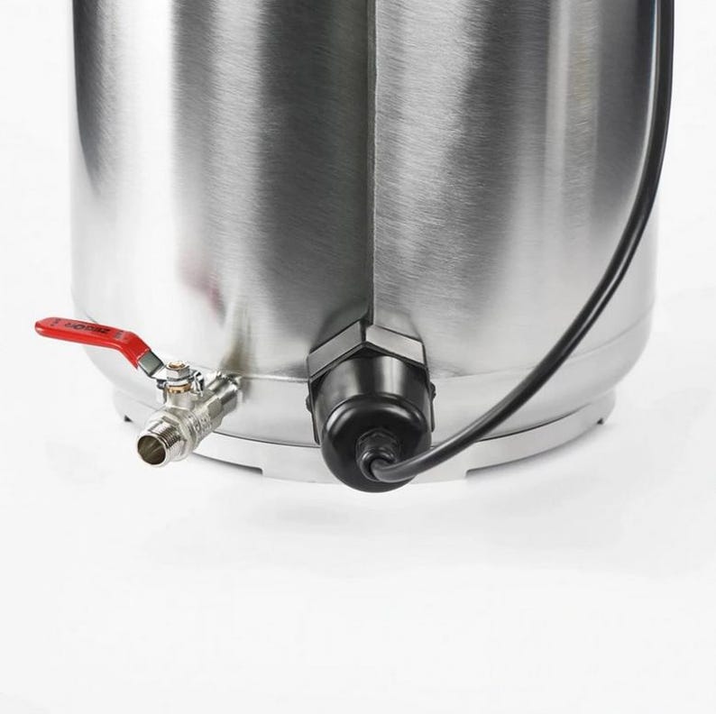May include: A cylindrical stainless steel vessel featuring a metallic finish, equipped with a silver-toned metal spigot with a red handle on the left side and a black electrical cable housing unit mounted on the lower right side of the base.
