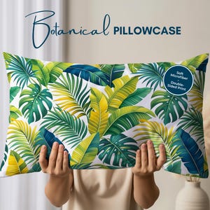May include: A rectangular pillowcase with a vibrant botanical print featuring green, yellow, and blue tropical leaves on a white background. The text "Botanical Pillowcase" is displayed at the top. The pillowcase is double-sided and made of soft microfiber.