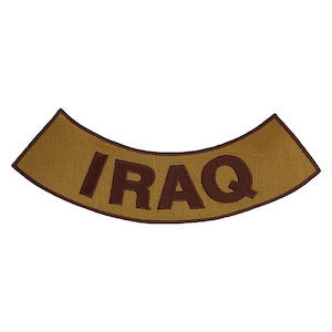 Op de afbeelding: Een gebogen, bruinbeige patch met het woord "IRAQ" in donkerbruin geborduurd. De patch heeft een getextureerd uiterlijk en een bruine rand. De tekst is over het midden van de patch gebogen.