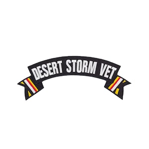 May include: A black embroidered patch with the words "DESERT STORM VET" in white block letters. The patch has a curved banner shape with yellow, red, and white accents on the ends.