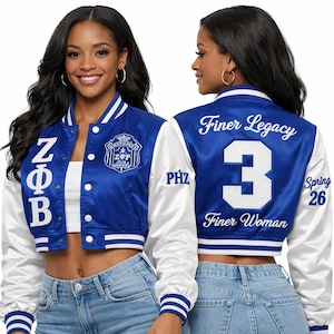Peut inclure: Veste universitaire courte en satin bleu et blanc. La veste présente des manches blanches, un corps bleu et des bordures blanches. L'avant affiche des lettres grecques et un écusson. Le dos porte les mots "Finer Legacy", le chiffre "3" et "Finer Woman".