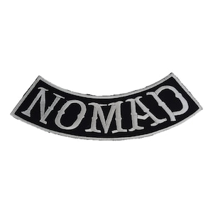 Pode incluir: Um patch preto e curvo com a palavra "NOMAD" bordada em fio prateado. O patch tem uma borda prateada e foi projetado para ser costurado em roupas ou acessórios. O patch é um design clássico.