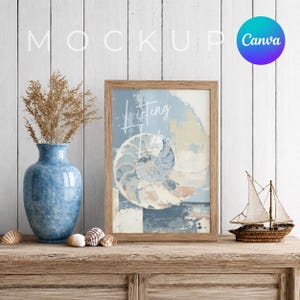 May include: A framed print with a nautilus shell design in shades of blue, beige, and white. The print is displayed on a wooden table with a blue vase holding dried plants, seashells, and a small sailboat model. The word "Listing" is visible on the print.