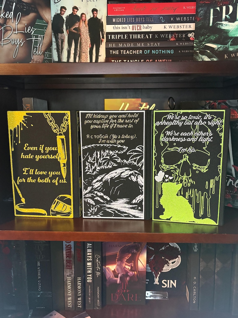 Puede incluir: Tres cubiertas de libros decorativas con fondos negros y acentos amarillos ne&oacute;n o verdes. Las cubiertas presentan citas e ilustraciones, incluyendo una calavera, un gato y una cadena. Los libros se exhiben en una estanter&iacute;a de madera con otros libros.