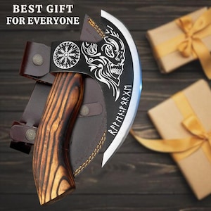 May include: A black and silver axe with a wooden handle and a leather sheath. The axe head has a skull design and runes engraved on it. The sheath has a Viking knot design.