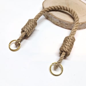 May include: A natural jute rope handle with two gold metal rings. The rope is knotted at each end to create a sturdy handle.