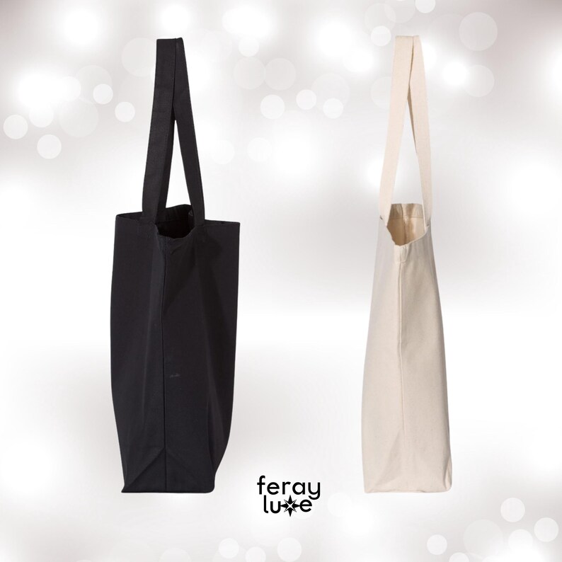 Puede incluir: Dos bolsas de tela, una negra y una blanca, con asas largas. Ambas bolsas est&aacute;n hechas de lona.