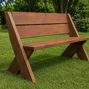 Puede incluir: Un banco de madera de color marrón oscuro con un respaldo horizontal de dos listones anchos y un asiento plano. El banco se apoya en dos patas robustas e inclinadas a cada lado que se cruzan para formar una base estable en forma de X.