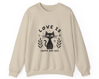 May include: A beige sweatshirt with a black cat illustration and the text "LOVE IS COFFEE AND CATS".
