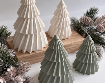 May include: Four conical tree-shaped ornaments with a pleated, fan-like texture. Two trees are matte white and two are sage green, arranged in varying heights on a rectangular wooden block. The design features sharp, vertical ridges.