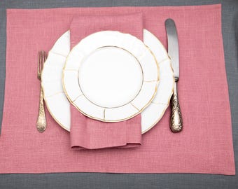 May include: A pink linen placemat with a white dinner plate and a white salad plate. A silver fork and knife are placed on the placemat.