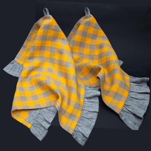 May include: Two yellow and grey checkered kitchen towels with ruffled edges. The towels are made of linen and have a farmhouse style.
