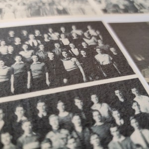 Op de afbeelding: Zwart-witfoto van een grote groep mensen die in rijen staan. De mensen zijn allemaal gekleed in formele kleding en lijken van een school of organisatie te zijn.