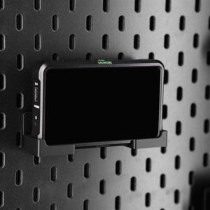May include: A black and silver Shinobi monitor with a black screen mounted on a pegboard wall.